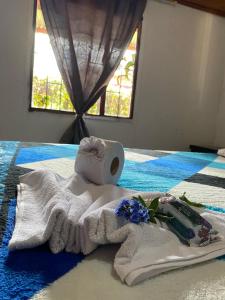Una toalla con un rollo de papel higiénico y flores en una cama en Casa Campestre Adela en Suesca