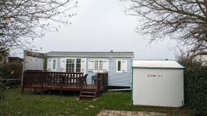 a small blue house with a gate and a building at Mobil Home 4Pers VO in Talmont