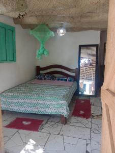 1 dormitorio con cama, ventana y alfombras rojas en Suíte beija-flor en Camaçari