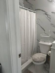 a bathroom with a white shower curtain and a toilet at Villa Clara SUITE - Little Havana in Miami