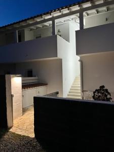 una grande casa bianca con una scala in un cortile di Case Vacanze "Bianco Mare" a Porto Pino