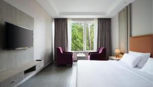 a hotel room with a bed and two chairs and a television at The Porto by lagom , Anjuna, vagator beach in Vagator