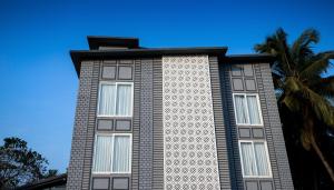 a tall building with windows and a palm tree at The Porto by lagom , Anjuna, vagator beach in Vagator