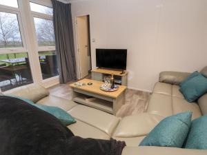 uma sala de estar com um sofá e uma televisão em Holmside em Market Drayton