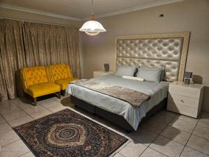 a bedroom with a large bed and a yellow chair at Vintage@1420 in Ngodini