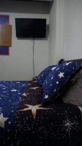 1 dormitorio con 1 cama con estrellas y TV en Hostal Palmas De Cocora, en Salento