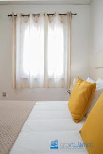 Bett mit gelbem Kissen vor dem Fenster in der Unterkunft Porto Sé Classic Terrace Apartment in Porto