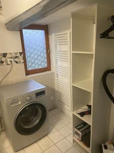 een wasruimte met een wasmachine en een raam bij La Guitoune in Beuzeville
