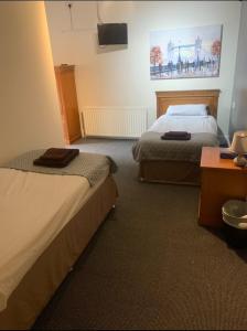 ein Hotelzimmer mit 2 Betten und einem Tisch in der Unterkunft The Coach House at The Bull Inn in Milton Keynes