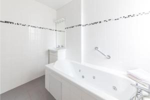 a white bathroom with a tub and a sink at Appartement Montparnasse in Paris