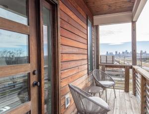un balcón de madera con 2 sillas y una puerta en Whiskey House with Rooftop Golf, City views! 8min to Downtown! Sleeps 9! en Nashville