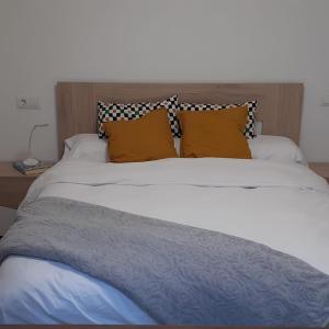 a large white bed with orange pillows on it at L'Amagatall in Ahín