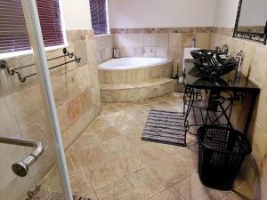 a bathroom with a shower and a tub and a sink at Adorable Designs in Pretoria