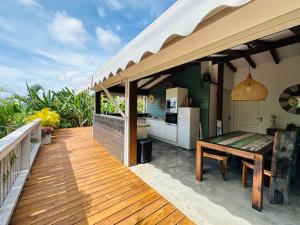 a wooden deck with a kitchen and a table at Villa Ô Perchée in Pointe-Noire