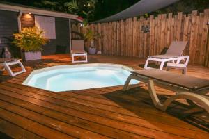 a pool on a deck with a bench and a chair at Villa Ô Perchée, Vue Mer Panoramique et Piscine Privée in Pointe-Noire