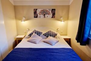 een slaapkamer met een blauw en wit bed met 2 kussens bij "O'REFUGE" Maison, 4 personnes, au cœur d'un golf 18 trous, accès piscines gratuit in Talmont