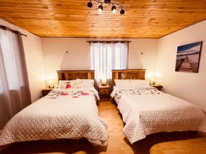two beds in a room with wooden ceilings at Cabaña Valle De La Laguna in Aquitania