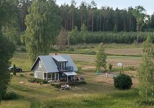 une maison avec un toit bleu dans un champ dans l'établissement Meza Skuki, à Vabole