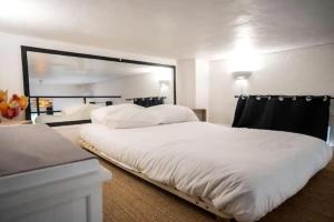 een slaapkamer met een groot wit bed en een spiegel bij Appartement avec mezzanine in Nice +1 foto