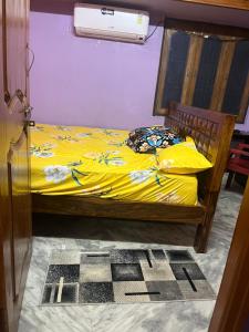 a bedroom with a bed with yellow sheets and a fan at SM Homestays 2 in Tirupati