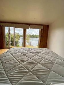 a bedroom with a large bed with a large window at Casa laguna quemchi in Quemchi