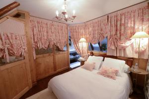 Schlafzimmer mit einem weißen Bett und rosa Vorhängen in der Unterkunft L'ESCALE DE CAMILLE in Murat
