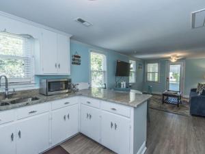 a kitchen with white cabinets and a living room at Changes In Latitudes in Folly Beach