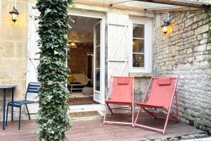 zwei rote Stühle auf der Veranda eines Hauses in der Unterkunft Le Jardin - Pl St Sauveur - Hypercentre in Caen