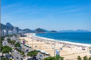 a beach with a lot of people and the ocean at Unhotel - Luxuoso Loft com Vista Mar na Praia de Copacabana in Rio de Janeiro