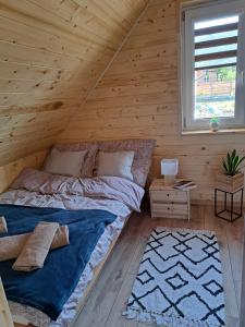 a bedroom with a bed in a wooden cabin at Całoroczne Domki Wypoczynkowe - Osada pod Górą in Ustrzyki Dolne