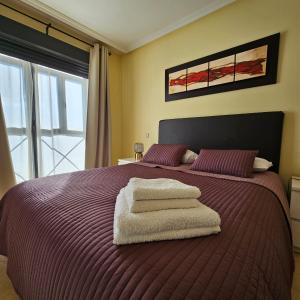 - une chambre avec un lit violet et des serviettes dans l'établissement Casa Adriego, à Riaza