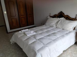 a white bed with white sheets and a wooden headboard at Casa da Praia in Praia de Mira