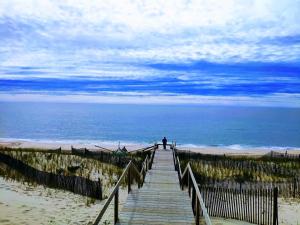 a person walking down a wooden boardwalk to the beach at Casa da Praia in Praia de Mira