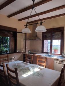 - une cuisine avec une table, des chaises et deux lumières dans l'établissement Casa Rural Leonor con piscina privada, à Casar de Palomero