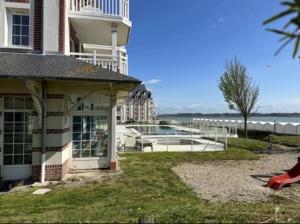 a building with a yard next to a body of water at Residence de la Plage Pierre et Vacances in Le Crotoy