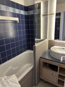 a blue tiled bathroom with a tub and a sink at Residence de la Plage Pierre et Vacances in Le Crotoy