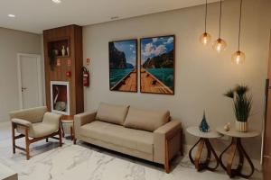 een woonkamer met een bank en twee schilderijen aan de muur bij Lindo apartamento em Guarapari - Novinho - Vista Maravilhosa in Guarapari