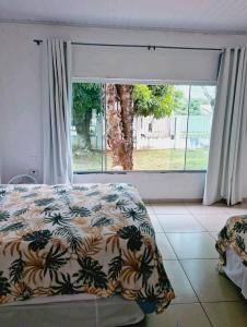 a bedroom with a bed and a large window at Casa Cataratas in Foz do Iguaçu