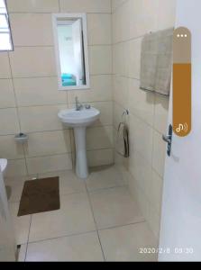 a white bathroom with a sink and a mirror at Casa Cataratas in Foz do Iguaçu