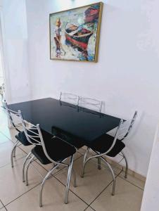 a black table with two chairs and a painting on the wall at Casa Cataratas in Foz do Iguaçu