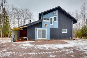 a blue house with a garage at Iron River Retreat with Sauna Walk to Ski Brule! in Iron River