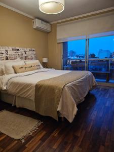 a bedroom with a large bed with a large window at Departamento Caseros in Salta +98 photos