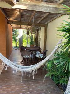 a hammock on a porch with a table and chairs at Morada dos Coqueiros in Garopaba