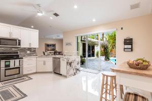 a kitchen with white cabinets and appliances and a patio at Tropical Oasis with Heated Pool in Boynton Beach