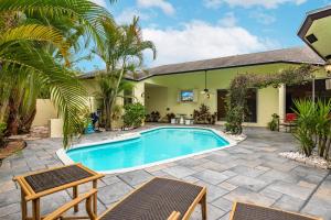 a villa with a swimming pool and palm trees at Tropical Oasis with Heated Pool in Boynton Beach