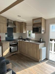 uma cozinha com armários de madeira e um forno com placa de fogão em Lovely 2-Bed Luxury Caravan in Newquay em Newquay
