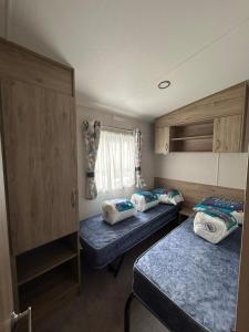 um pequeno quarto com 2 camas e uma janela em Lovely 2-Bed Luxury Caravan in Newquay em Newquay