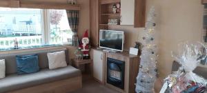 a living room with a santa claus sitting next to a fireplace at Immaculate 3-Bed Caravan with Hot Tub in Lincoln
