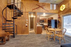 a kitchen and dining room with a spiral staircase in a cabin at Iron River Condo with Gas Grill Near Skiing and Hiking in Iron River