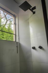 a white bathroom with a shower and a window at Studios Pinhal in Santo Antônio do Pinhal